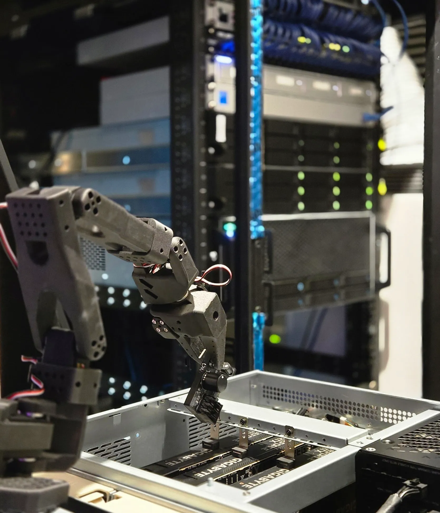 SO-ARM101 robot arm posed atop a server during fan-controller install.